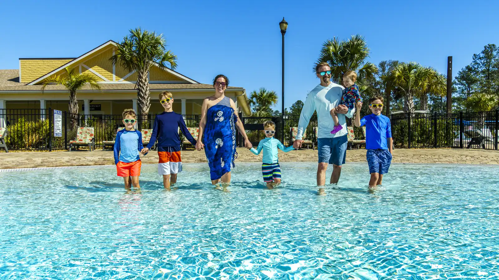 Family, parents and kids holding hands in the pool at Island Oaks