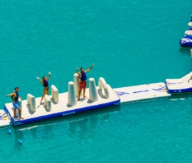 Aerial view of Island Oaks guests waving on the inflatable obstacle course in the Swimming Lake