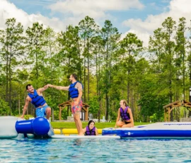 Island Oaks guests balancing on the inflatable obstacle course in the Swimming Lake