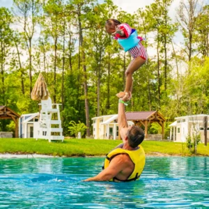 Father balancing young daughter on his raised hand in the Island Oaks Swimming Lake