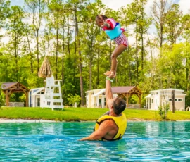 Father balancing young daughter on his raised hand in the Island Oaks Swimming Lake