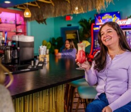 Woman holding a frozen cocktail and chatting at The Palms bar