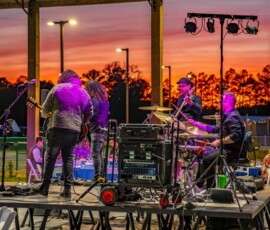 Live band playing outdoors at sunset under an event pavilion at Island Oaks