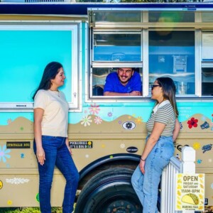 Friends in front of the Salsa & Sizzle food truck, which is covered in stickers and painted flowers