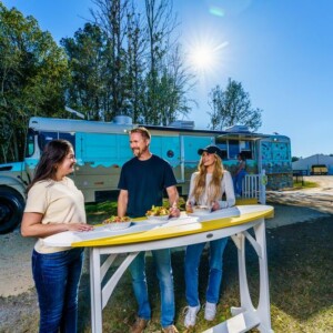People sitting at a surfboard-shaped table in front of the Salsa & Sizzle food truck