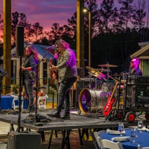 Live band performing on stage at sunset during an outdoor catered event at Island Oaks