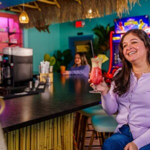 Woman holding a frozen cocktail and chatting at The Palms bar