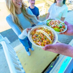 Woman receiving taco and salad bowls from Salsa & Sizzle food truck